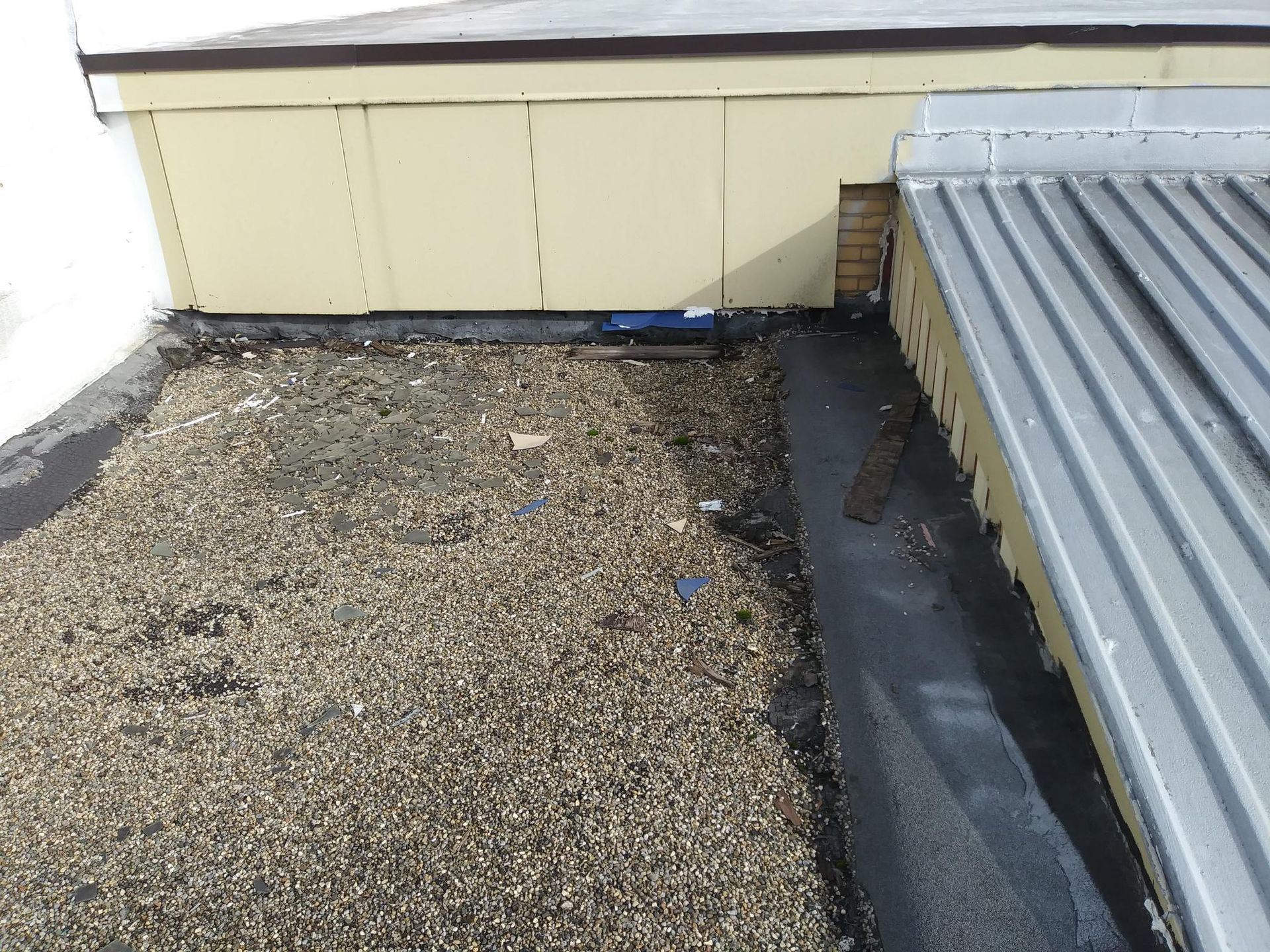 A roof with a metal roof and gravel on it.