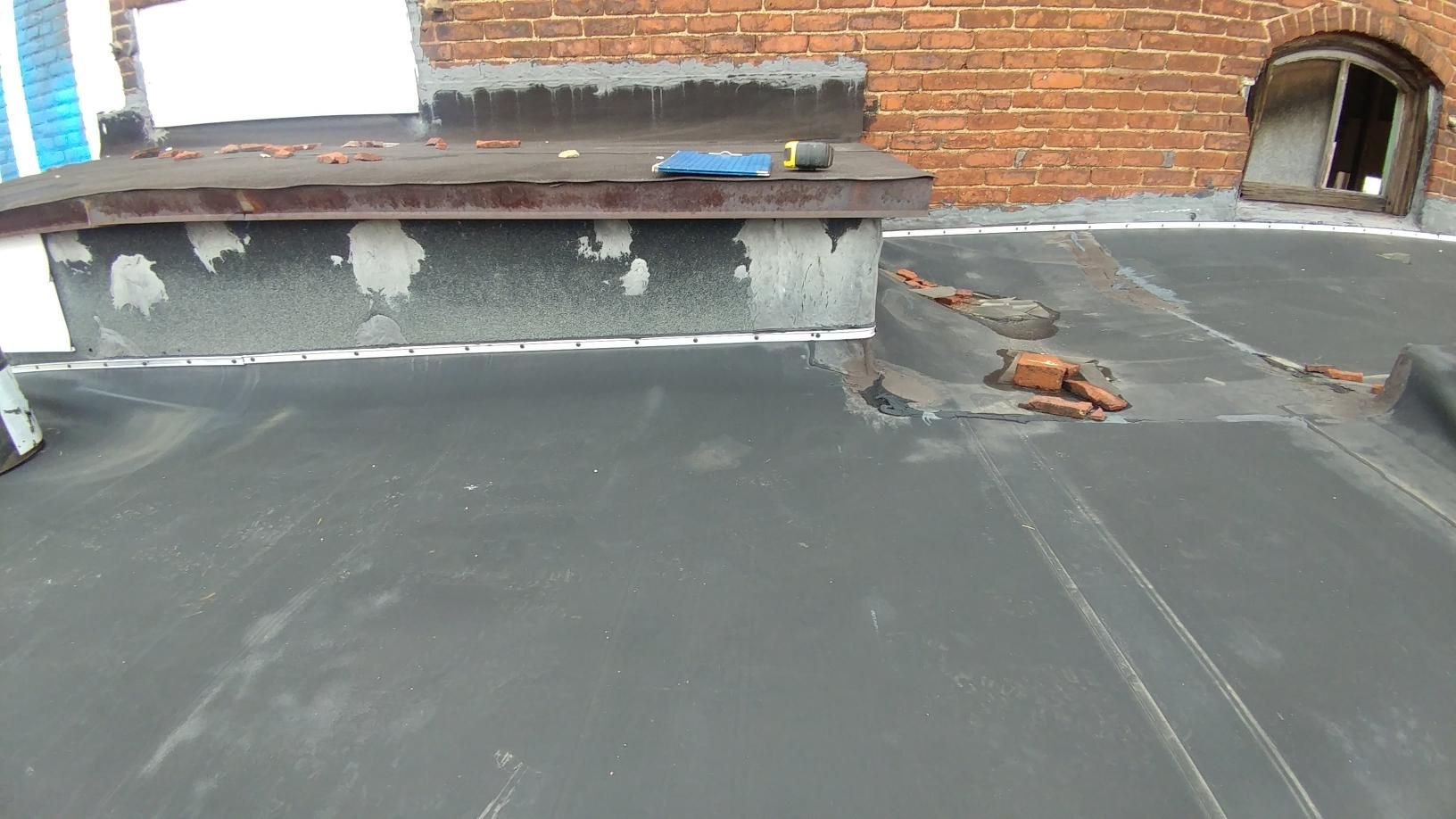 A black roof with a brick wall in the background.