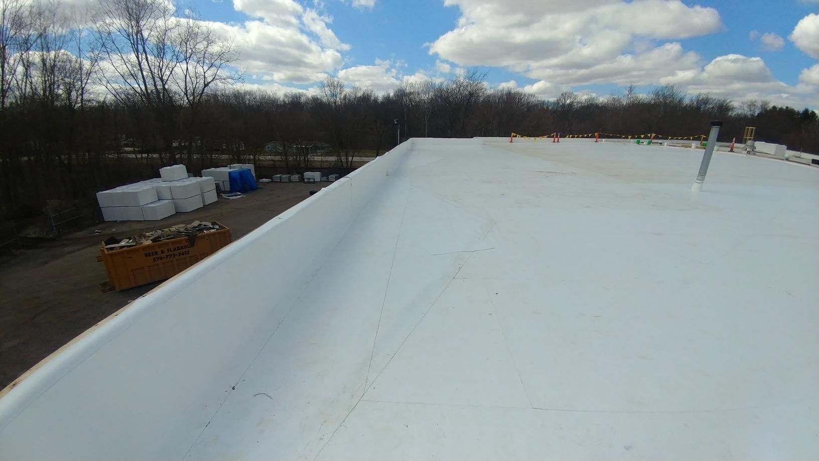 A white roof with a blue sky and clouds in the background.