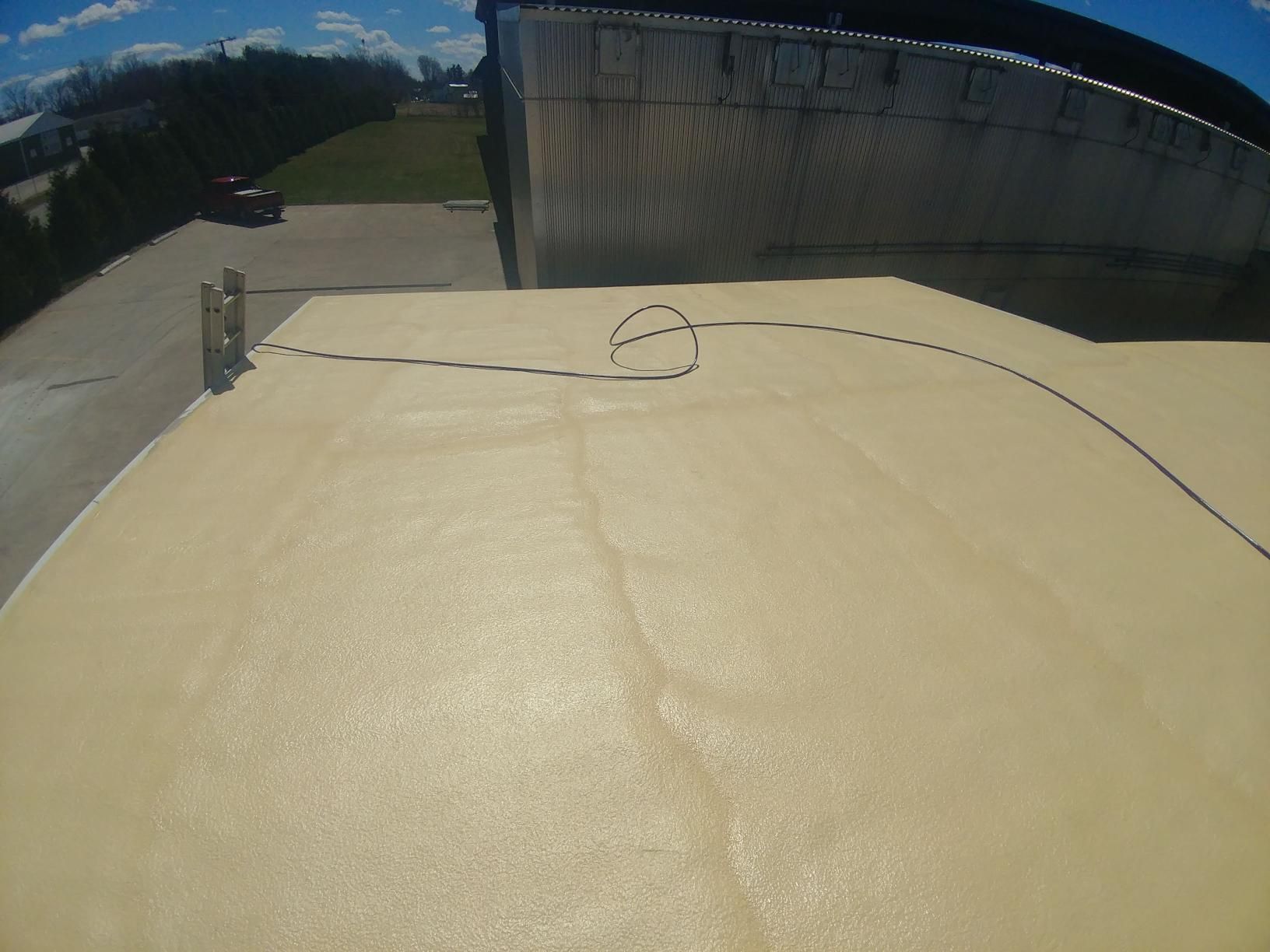 A roof with a hose attached to it and a building in the background.