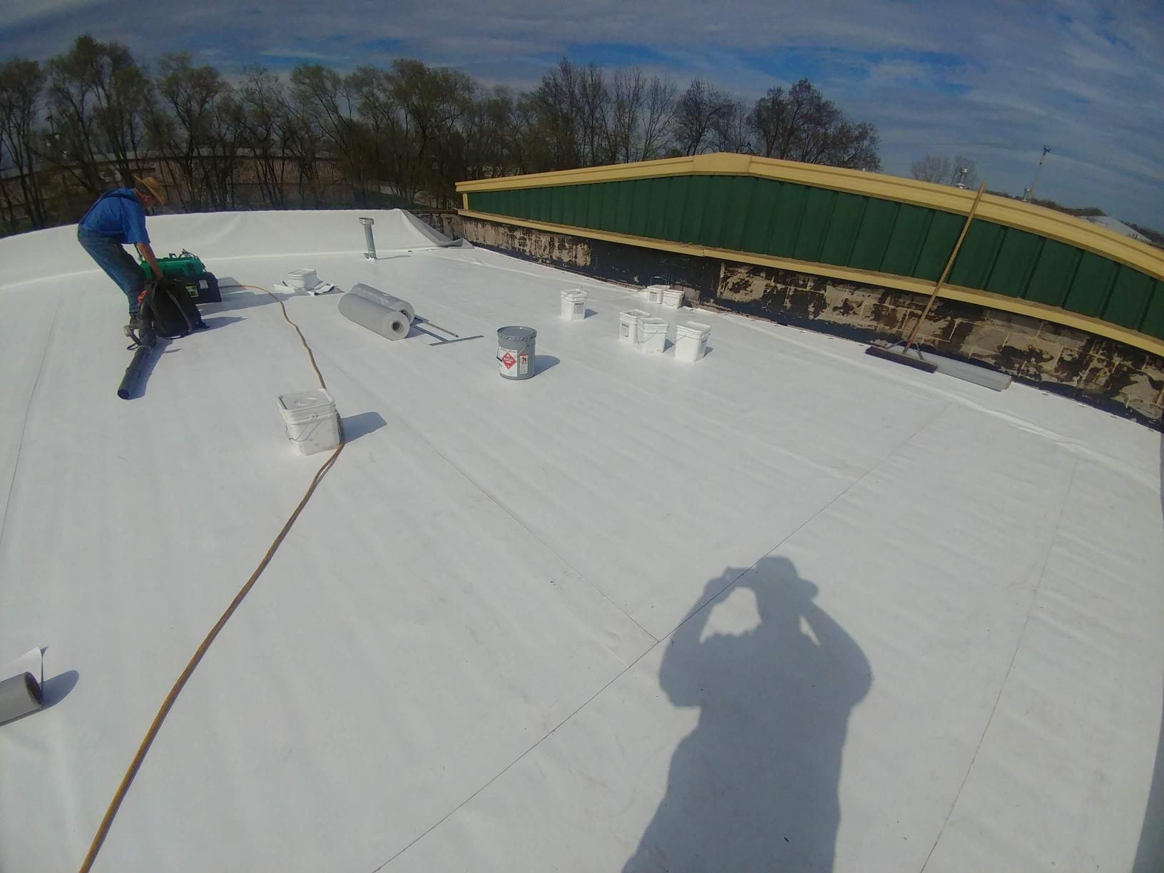 A man is standing on top of a white roof.