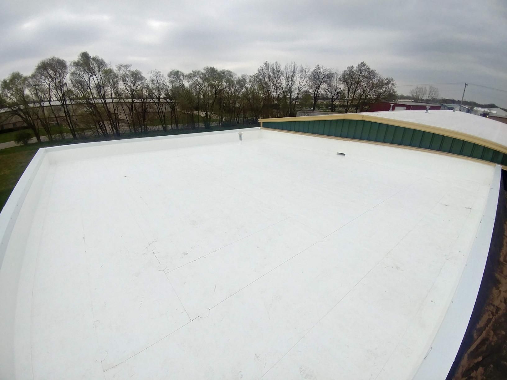 An aerial view of a white roof with trees in the background