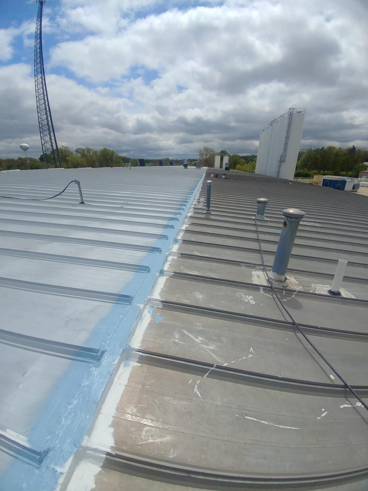 The roof of a building is being painted blue and white.