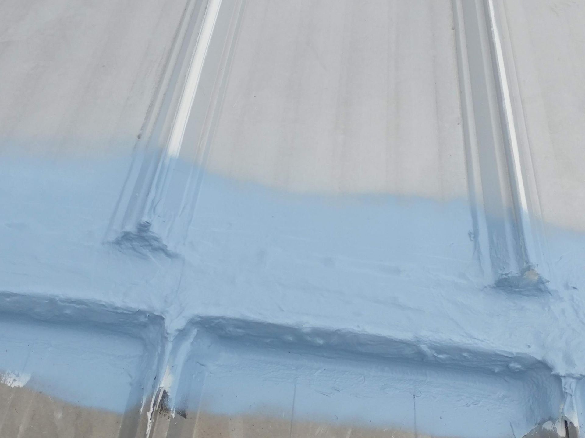 A blue liquid is being poured on a wooden surface.