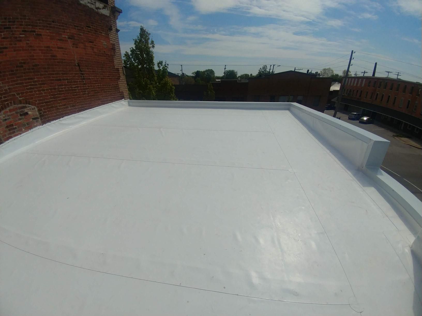 A white roof with a brick building in the background.
