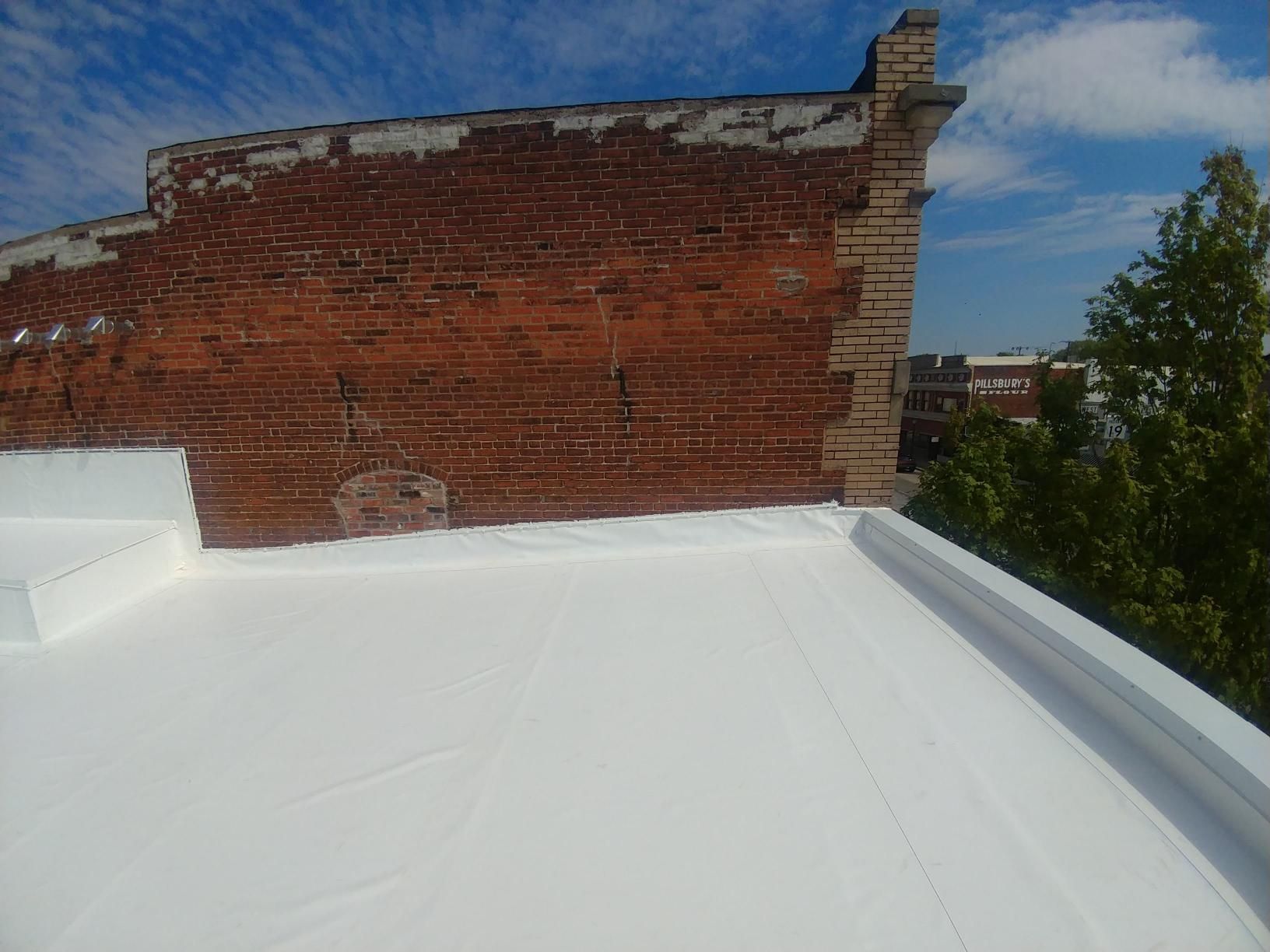 A white roof with a brick wall in the background