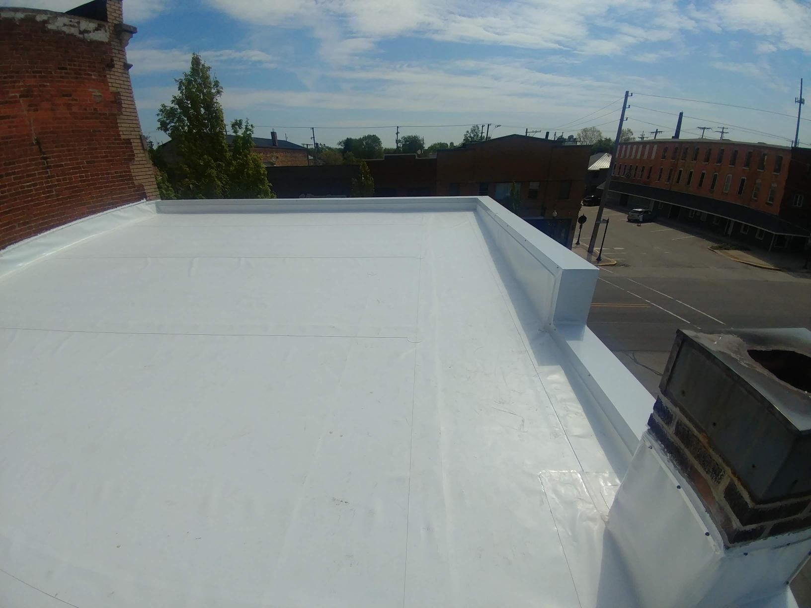 A white roof with a chimney on the side of a building.