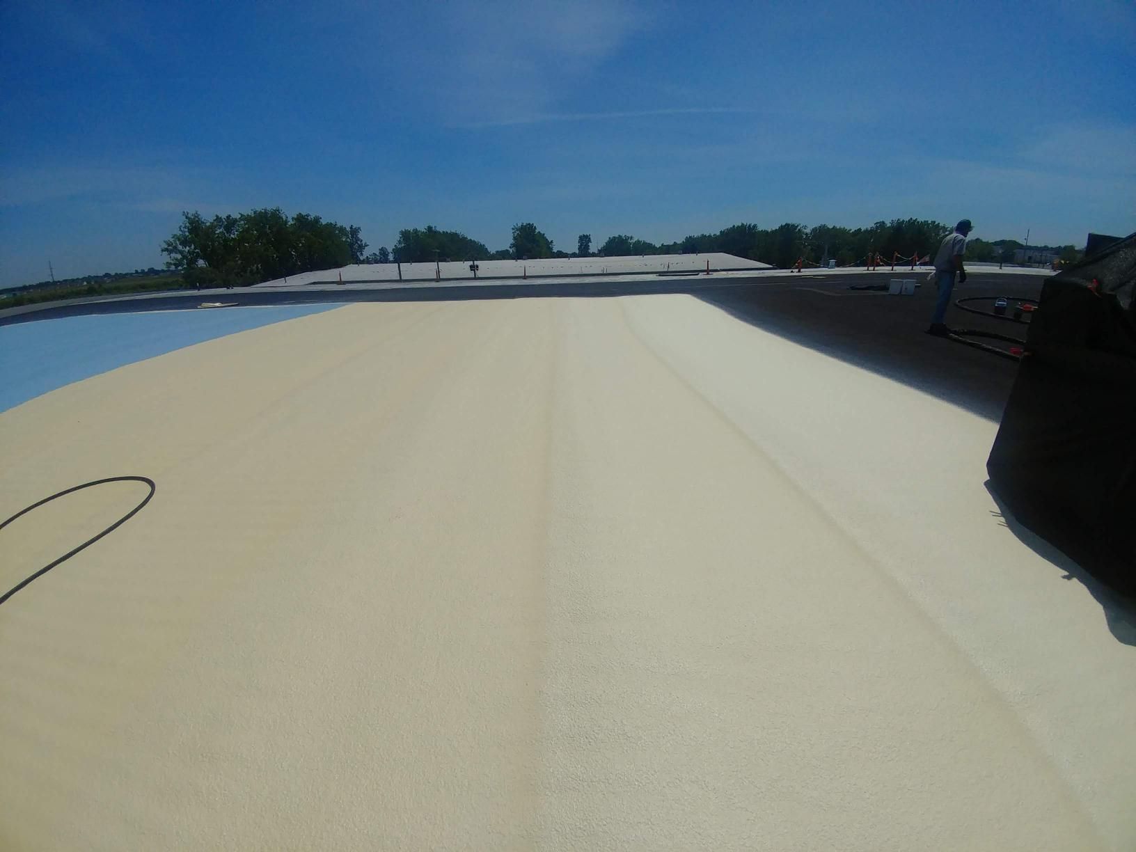 A person is standing on a roof with a blue sky in the background.