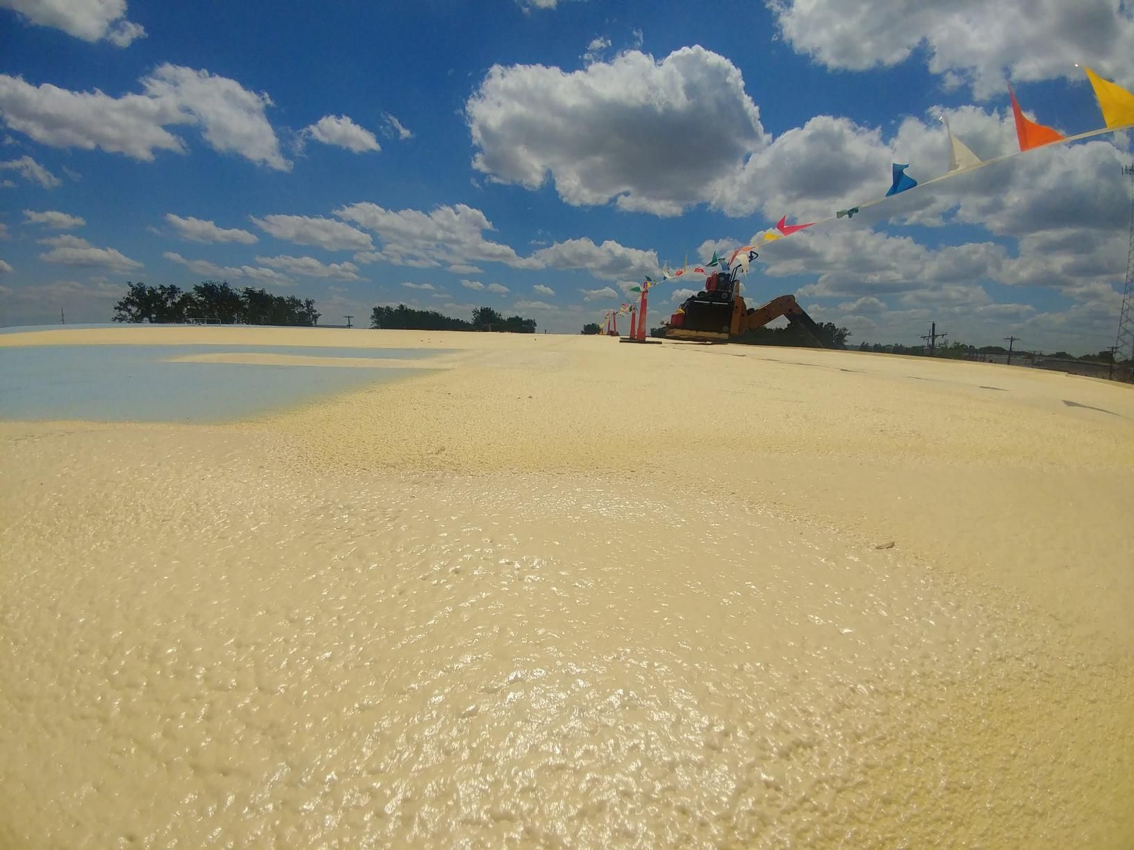 A sandy beach with a blue sky and clouds in the background