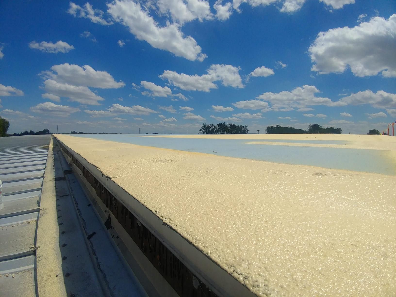 A roof with a blue sky and white clouds in the background