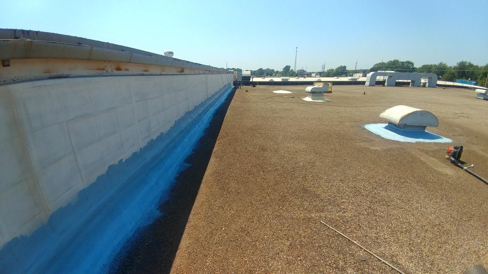 The roof of a building is being painted blue and white.