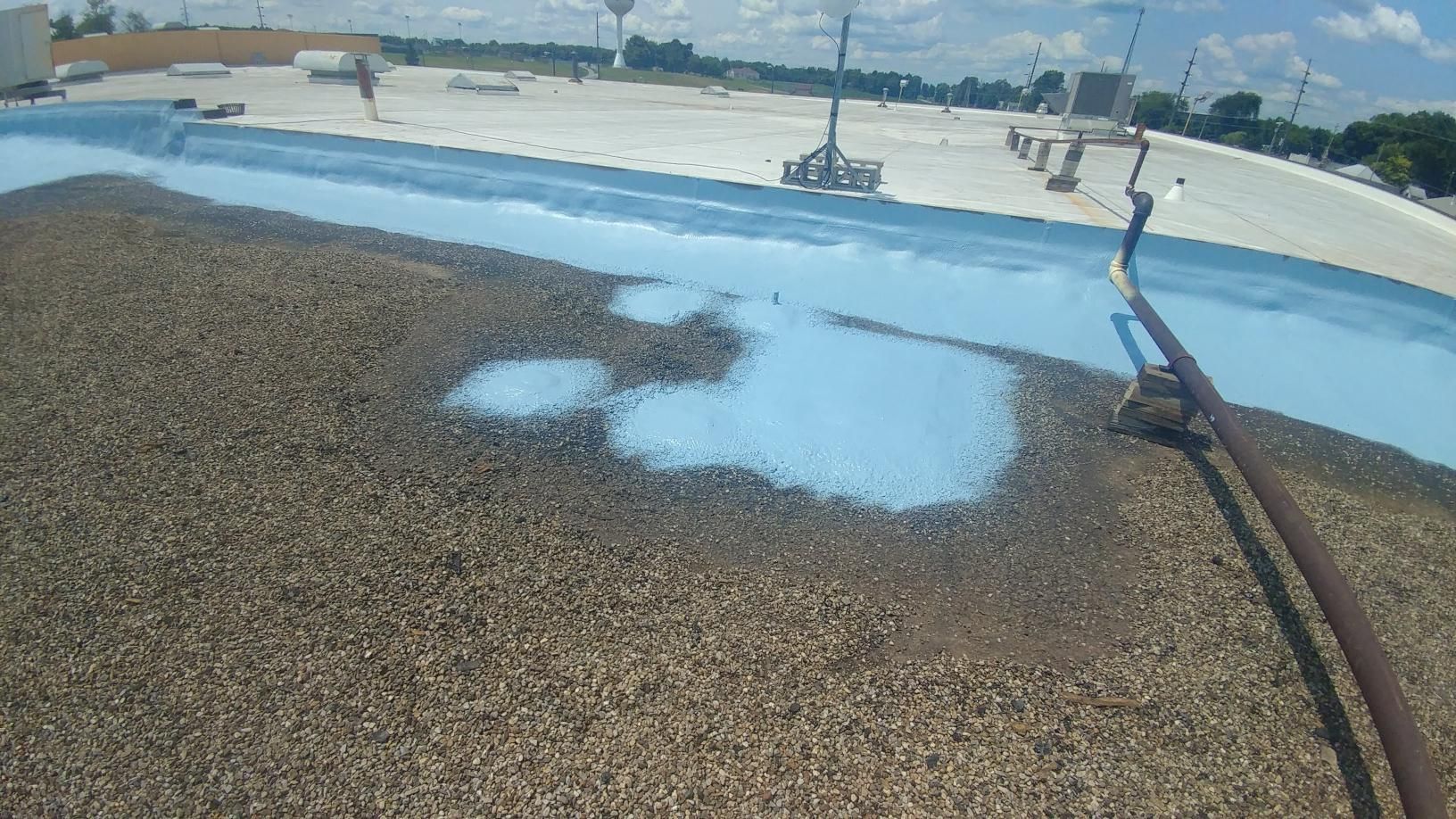A person is standing on a roof with a hose.