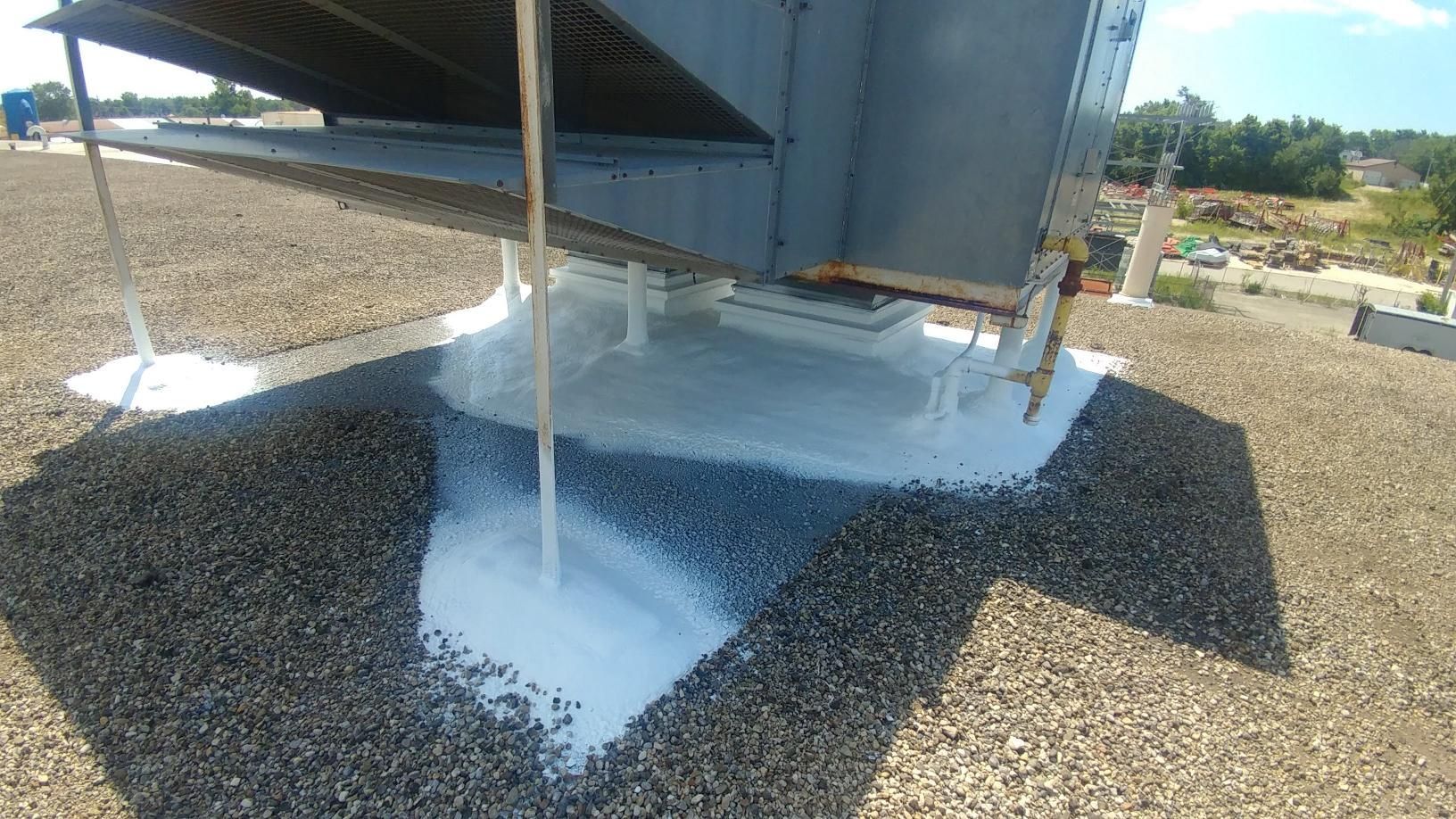 A large fan is sitting on top of a gravel roof.