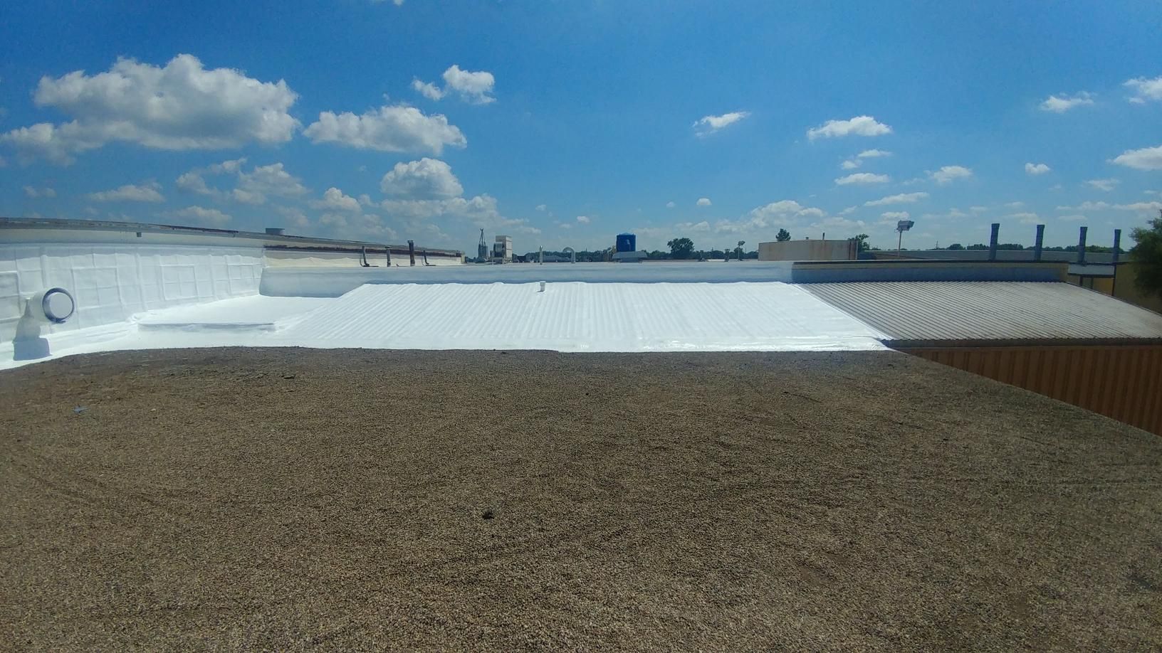 A roof with a white coating on it and a blue sky in the background.