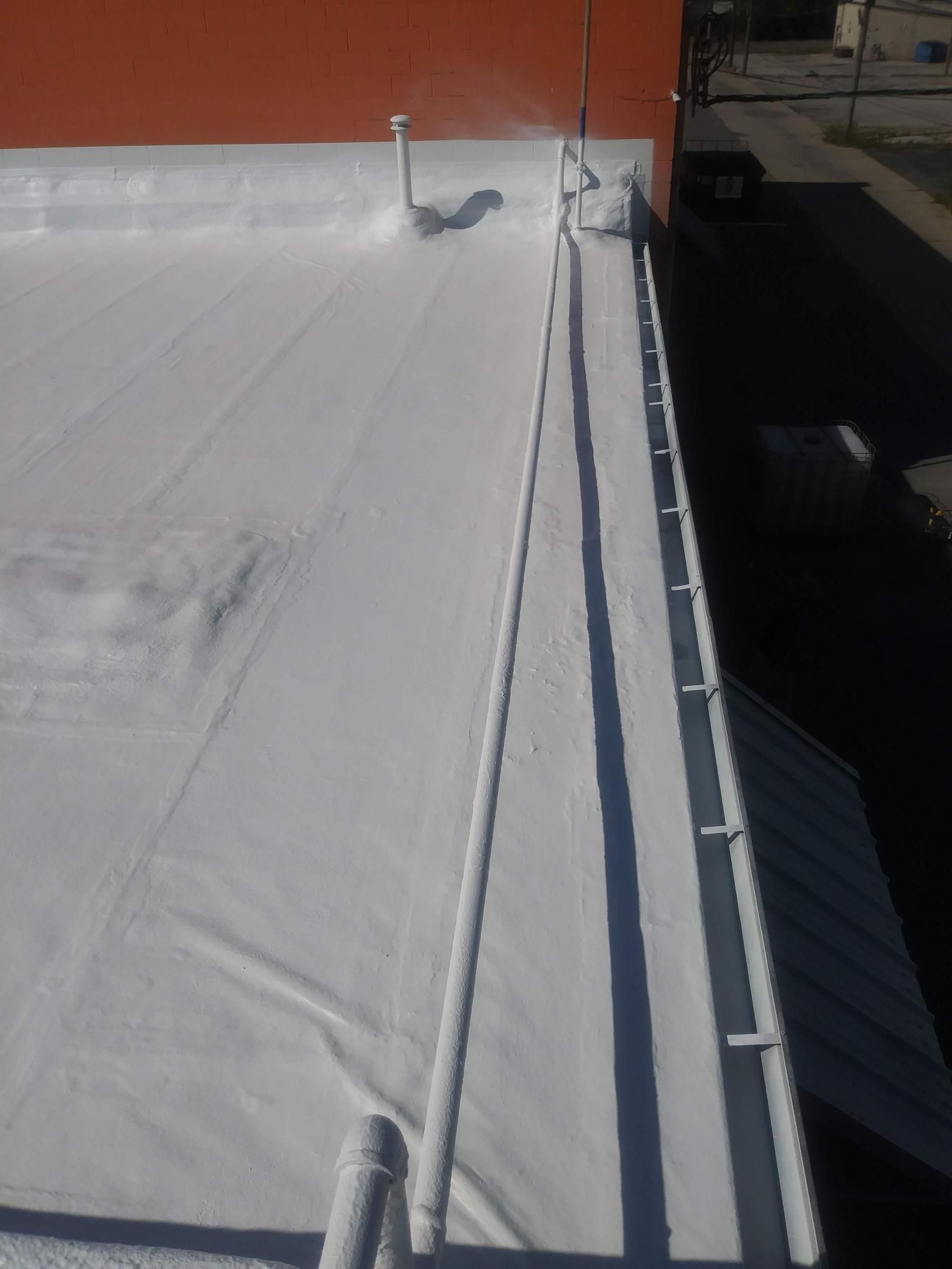 A white roof with a red building in the background