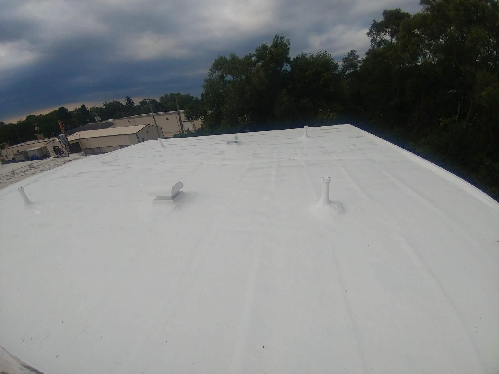 A white roof with a lot of trees in the background.