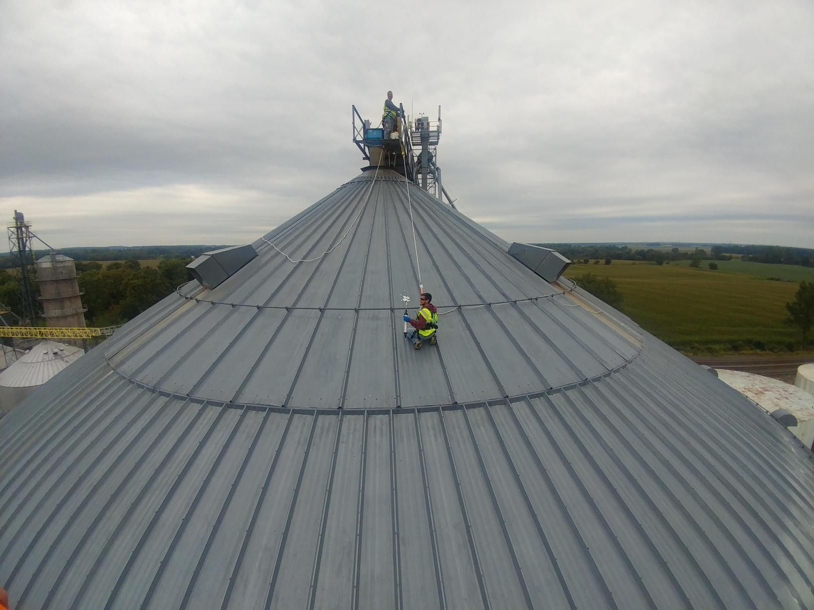 Two men are working on the roof of a large building.
