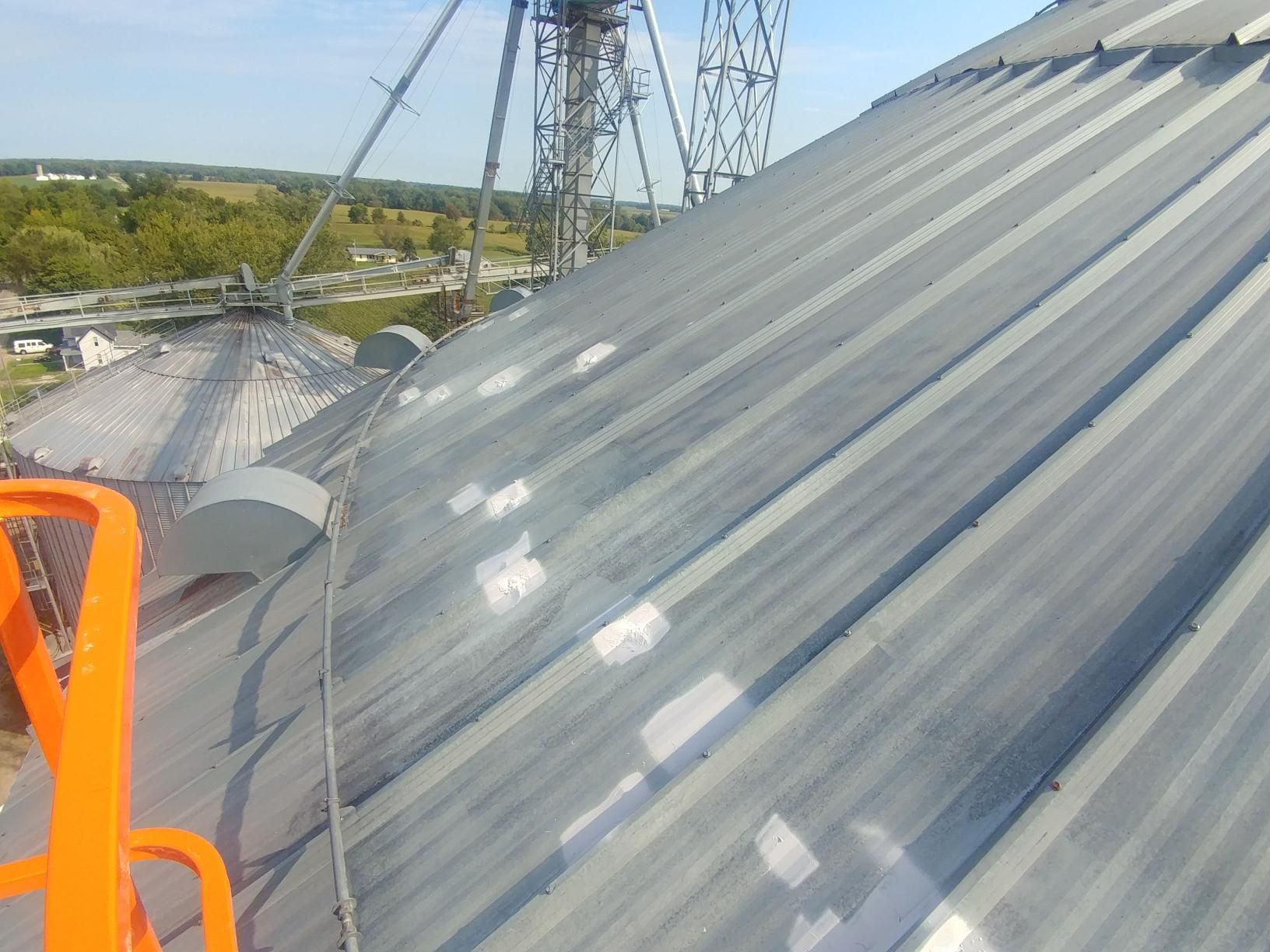 The roof of a building is being painted with white paint