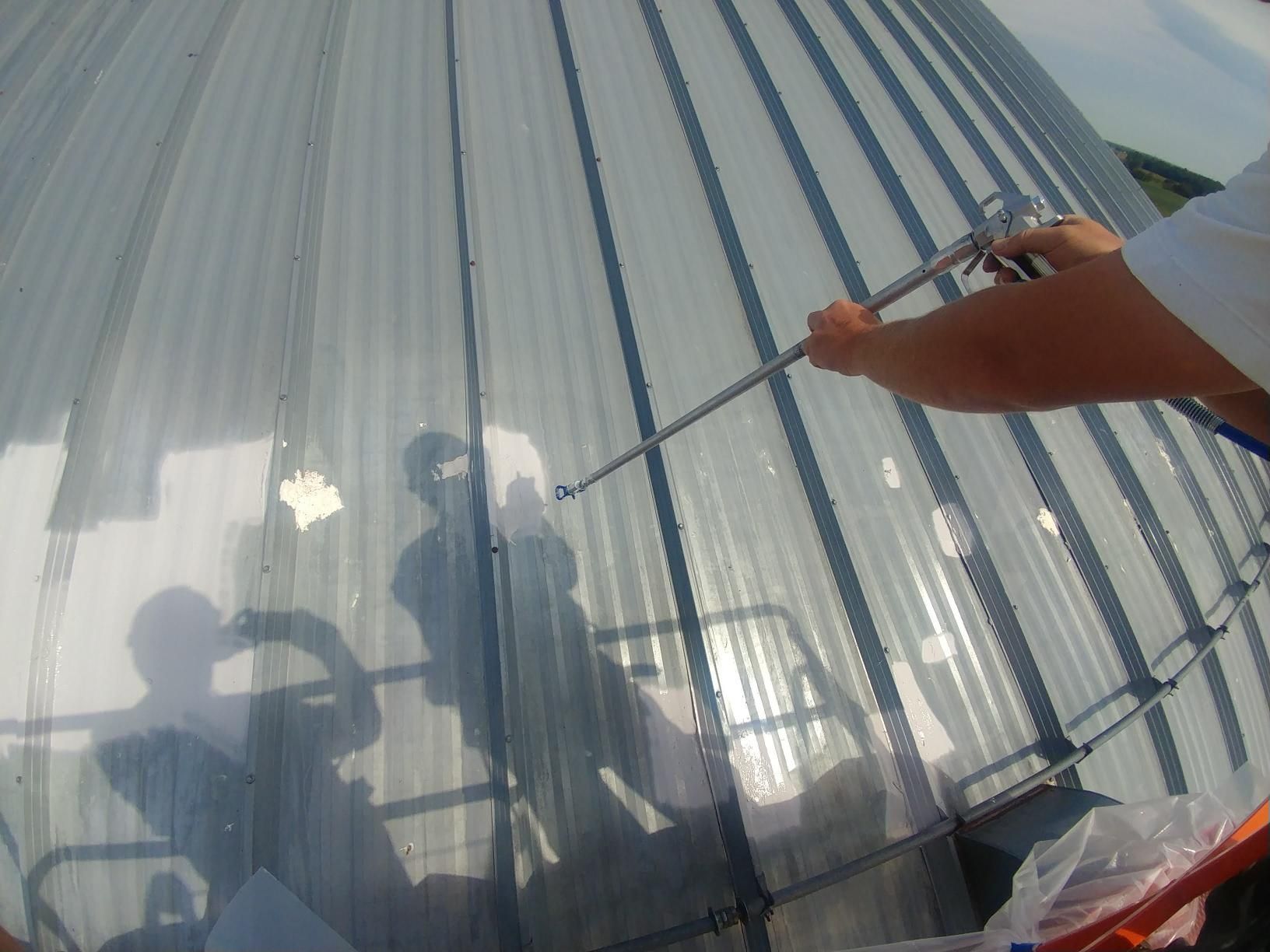 A person is spraying something on a clear roof