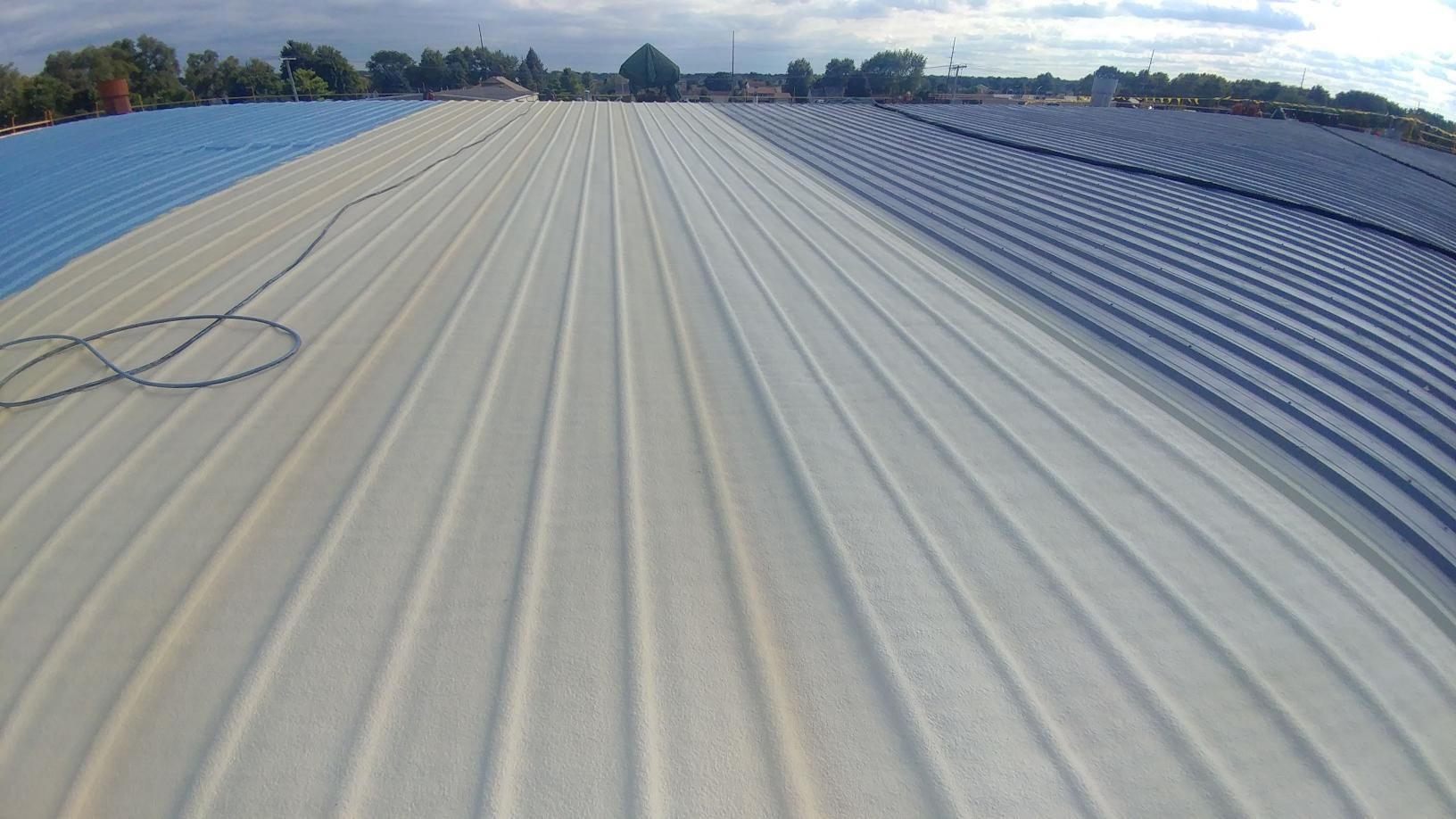 The roof of a building is being painted blue and white.