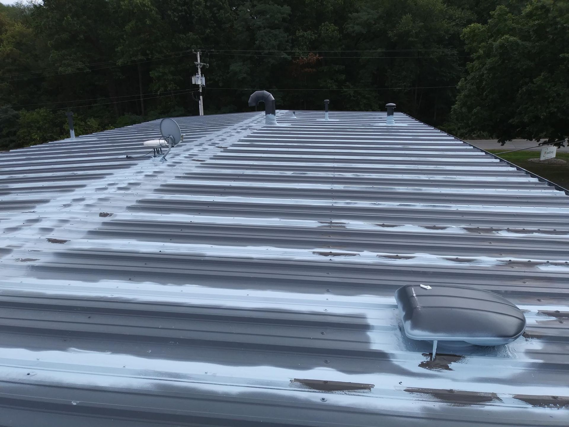 A roof with a fan on it and trees in the background.