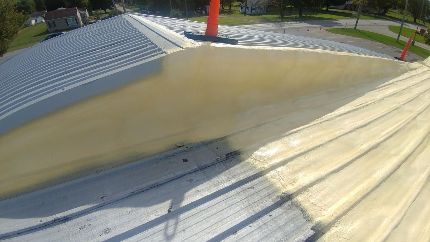 A roof with a chimney on it is being painted.