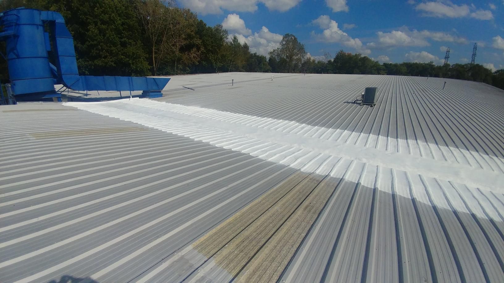 The roof of a building is being painted white.