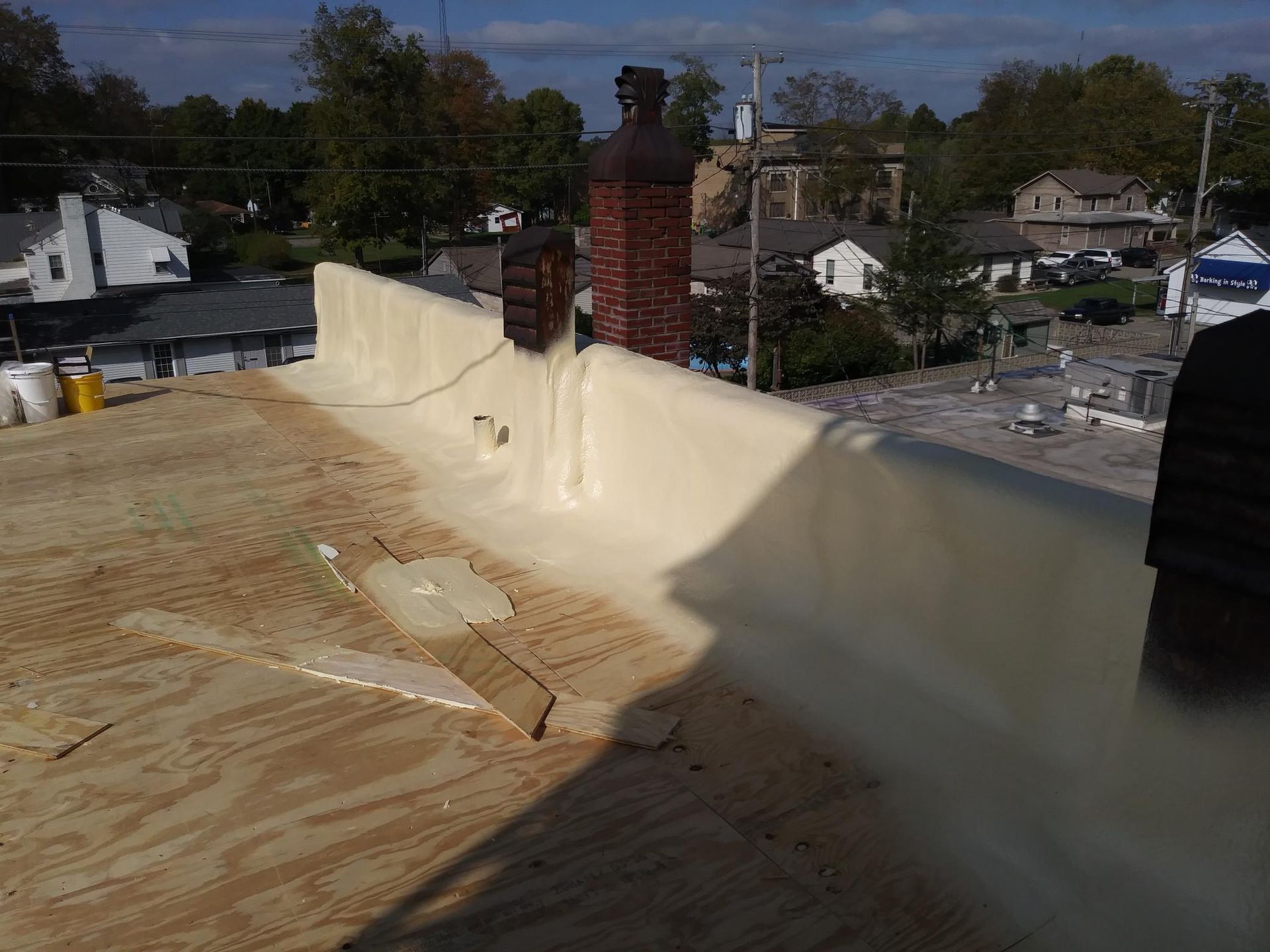 A roof with a chimney on it is being sprayed with foam