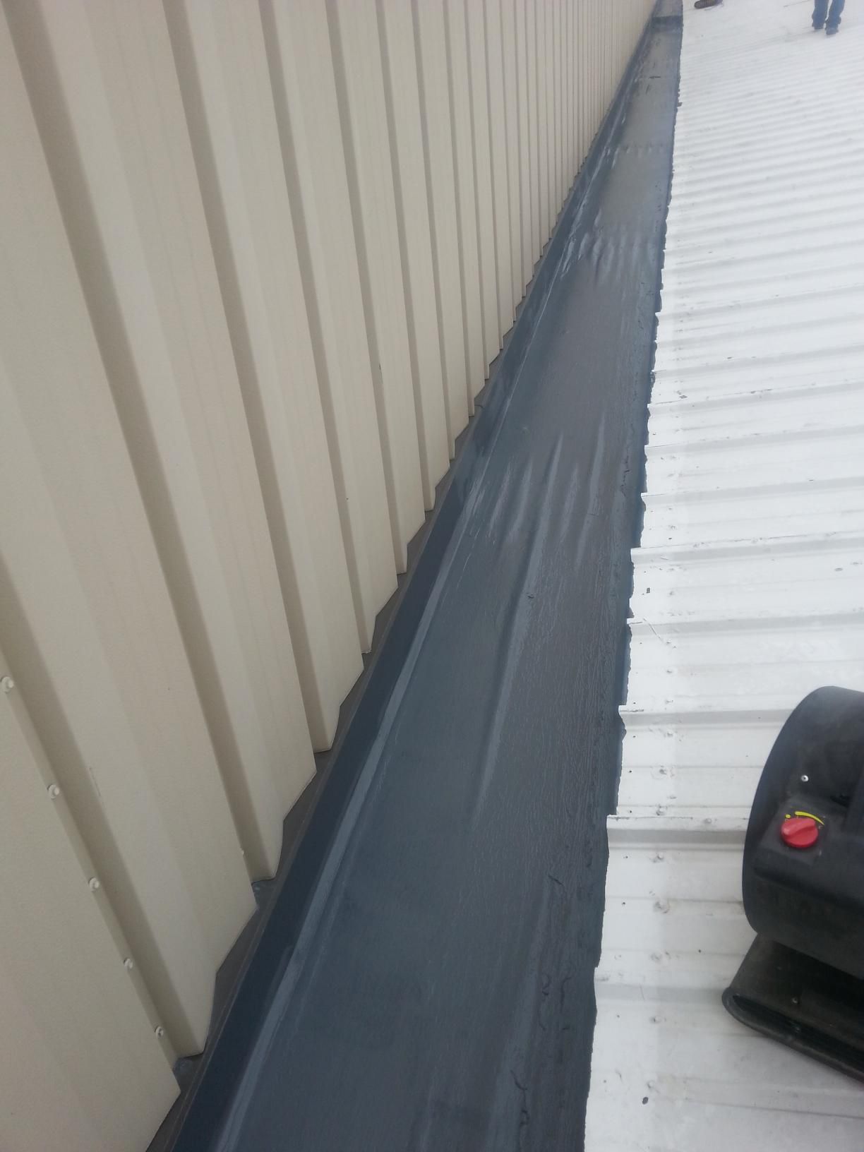 A person is working on a roof next to a building.