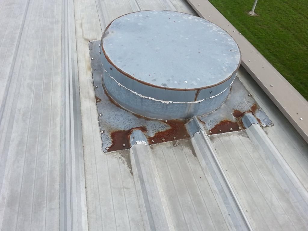 A round metal object is sitting on top of a metal roof.