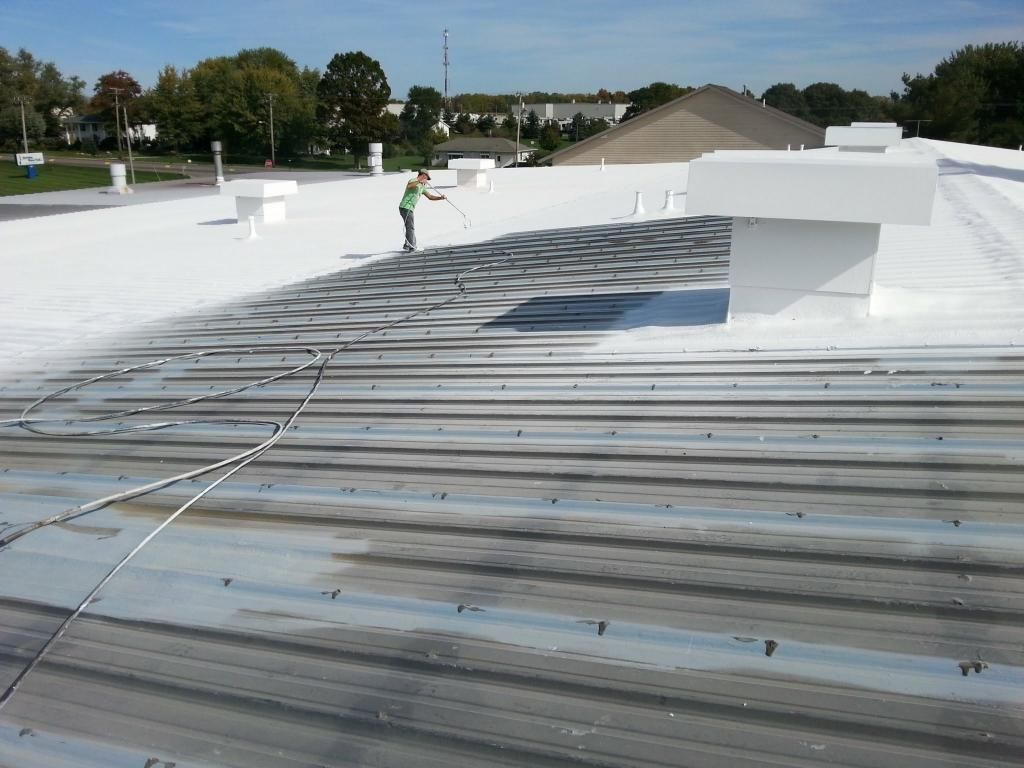 A man is painting a roof with white paint