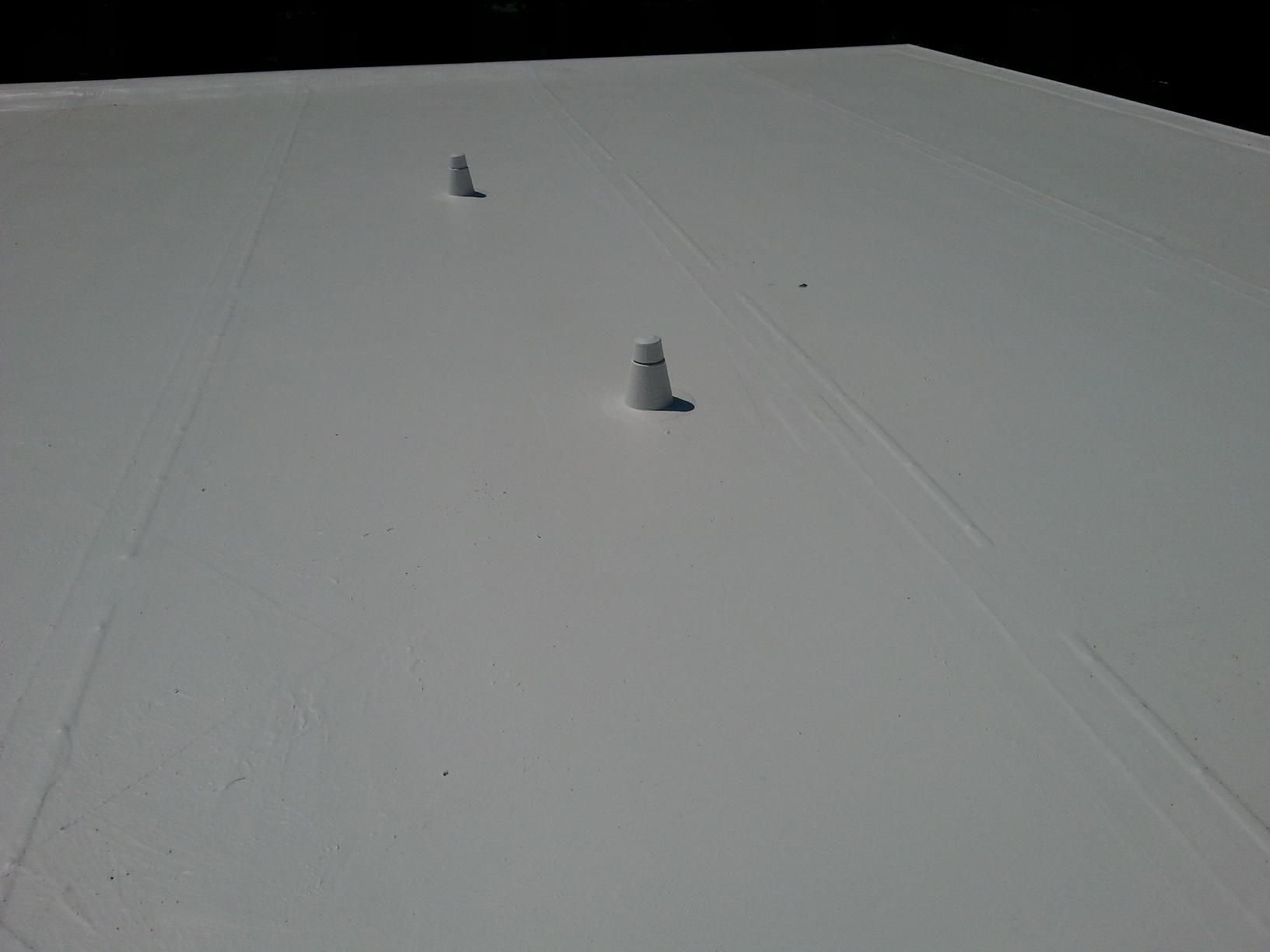 Two cones are sitting on top of a white roof.