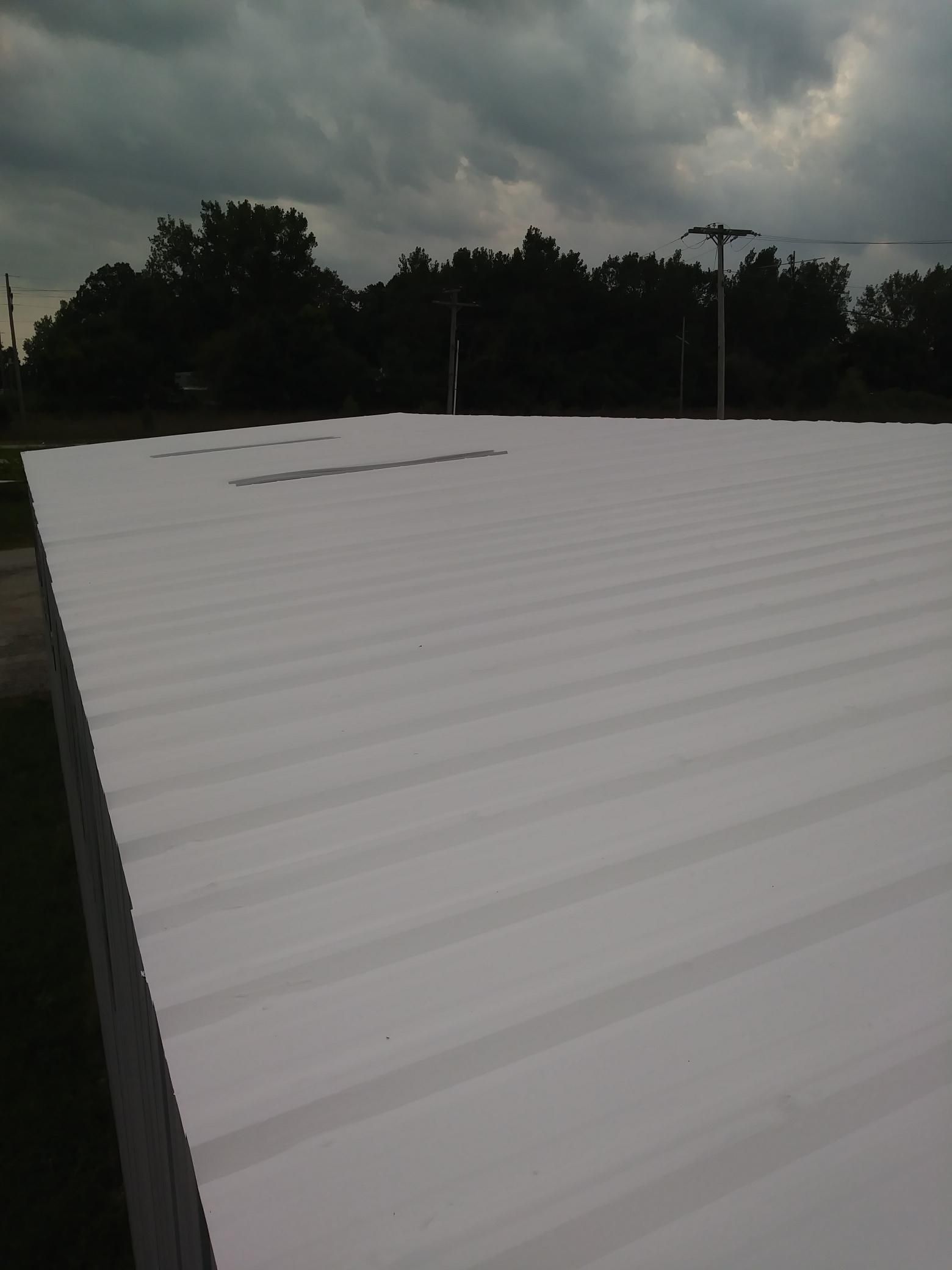 A large white roof with trees in the background on a cloudy day