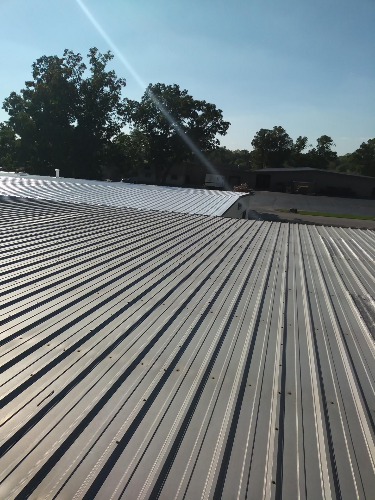 A close up of a metal roof with trees in the background