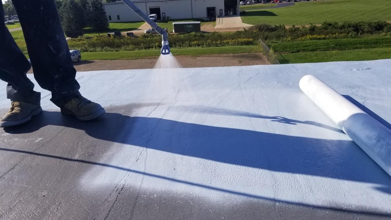A person is spraying a roof with a sprayer.