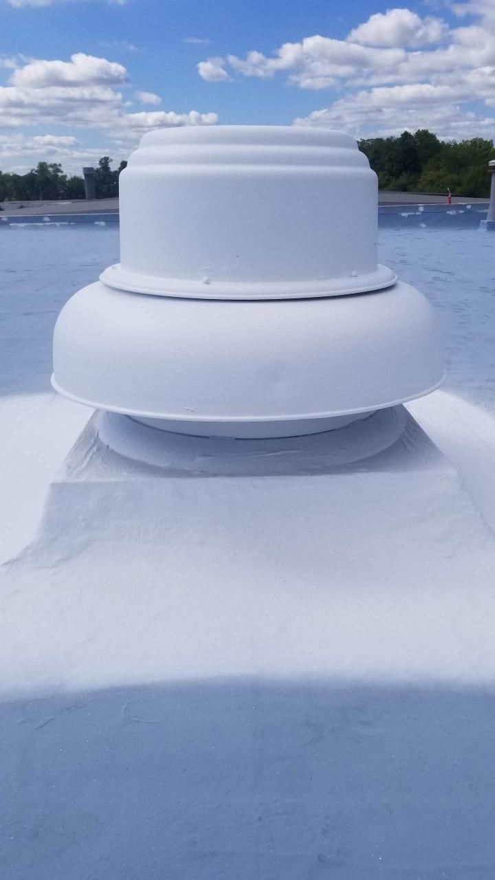 A white vent on top of a blue roof with a blue sky in the background.
