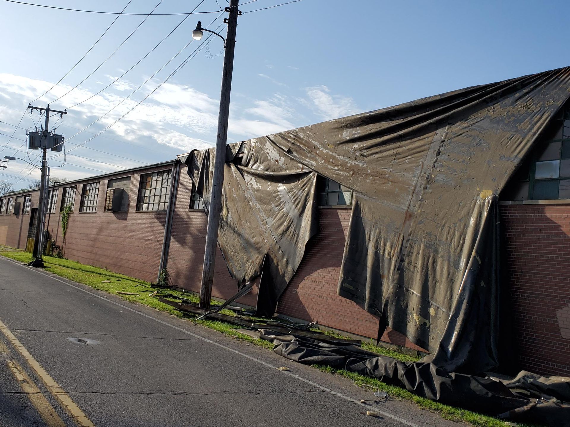 A large tarp is covering the side of a brick building