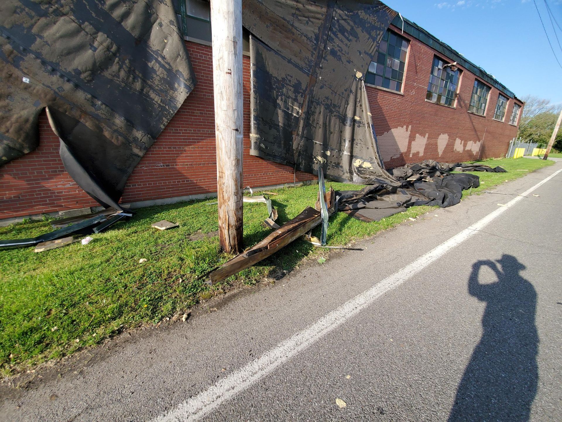 A person is taking a picture of a brick building next to a road.