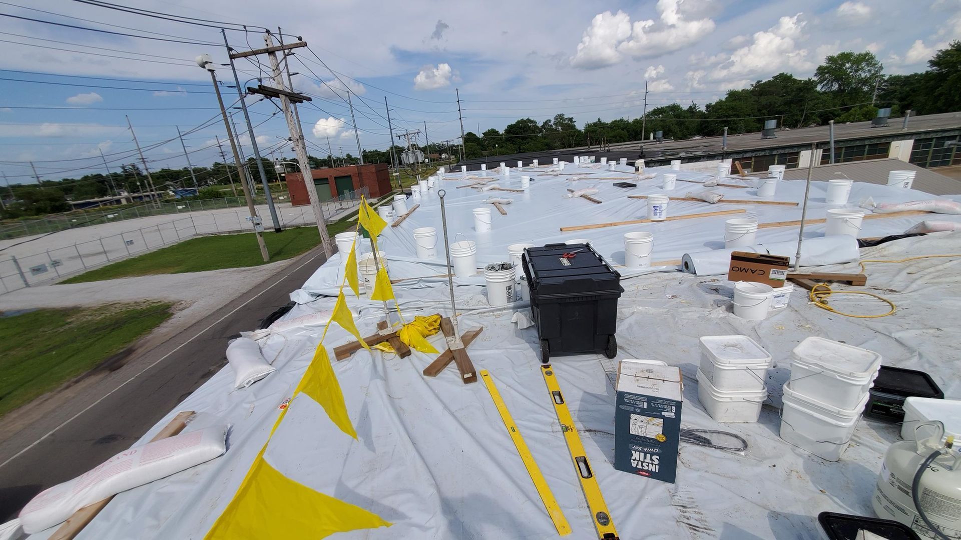 A roof with buckets of paint and yellow flags on it.