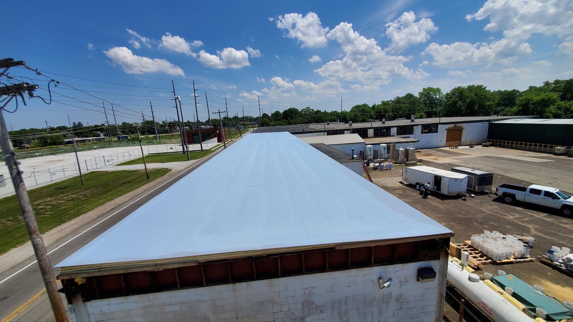 An aerial view of a roof of a building with trucks parked on the side of the road.