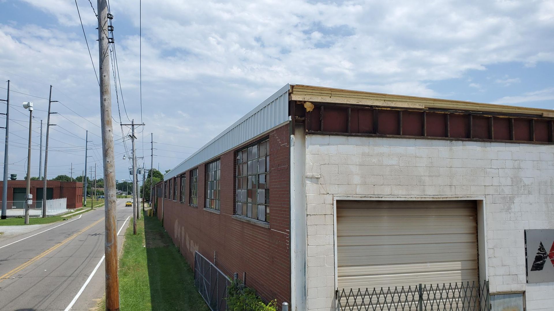 A brick building with a garage door is next to a road.