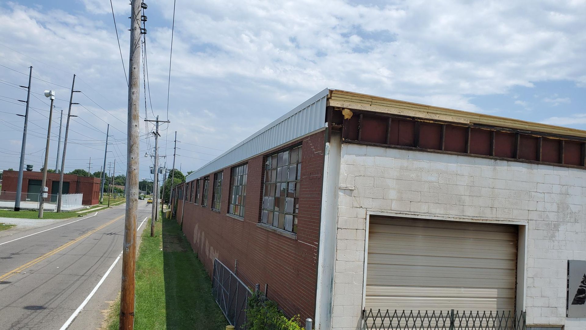 A brick building with a white garage door is next to a road.