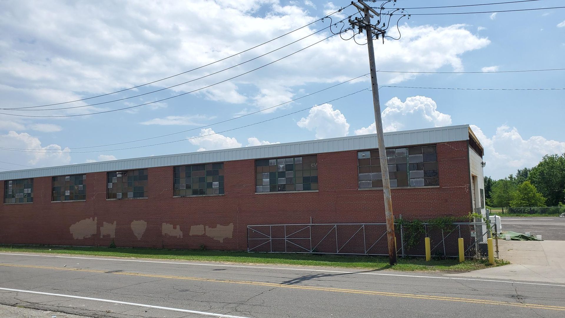 A large brick building is sitting on the side of a road next to a power line.
