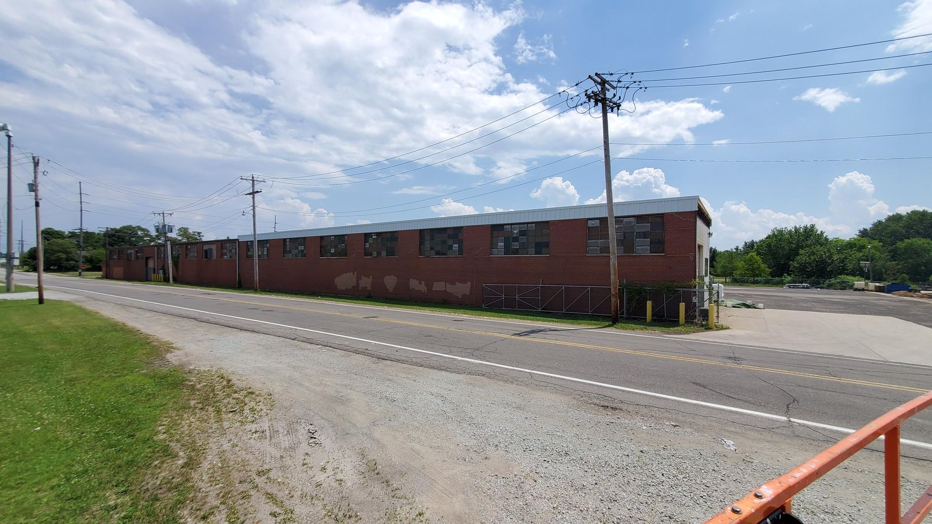 A large brick building is sitting on the side of a road next to a gravel road.