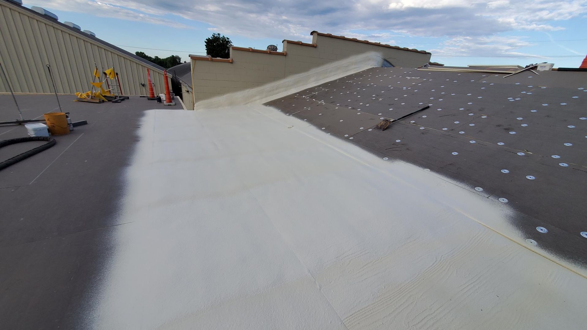 A person is painting a roof with white paint.