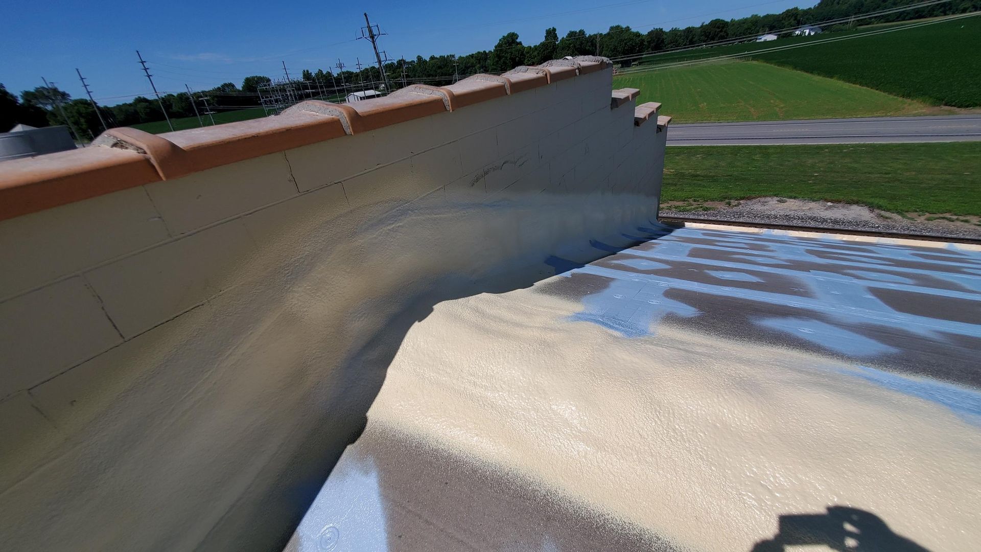 A shadow of a person is cast on a concrete surface next to a wall.