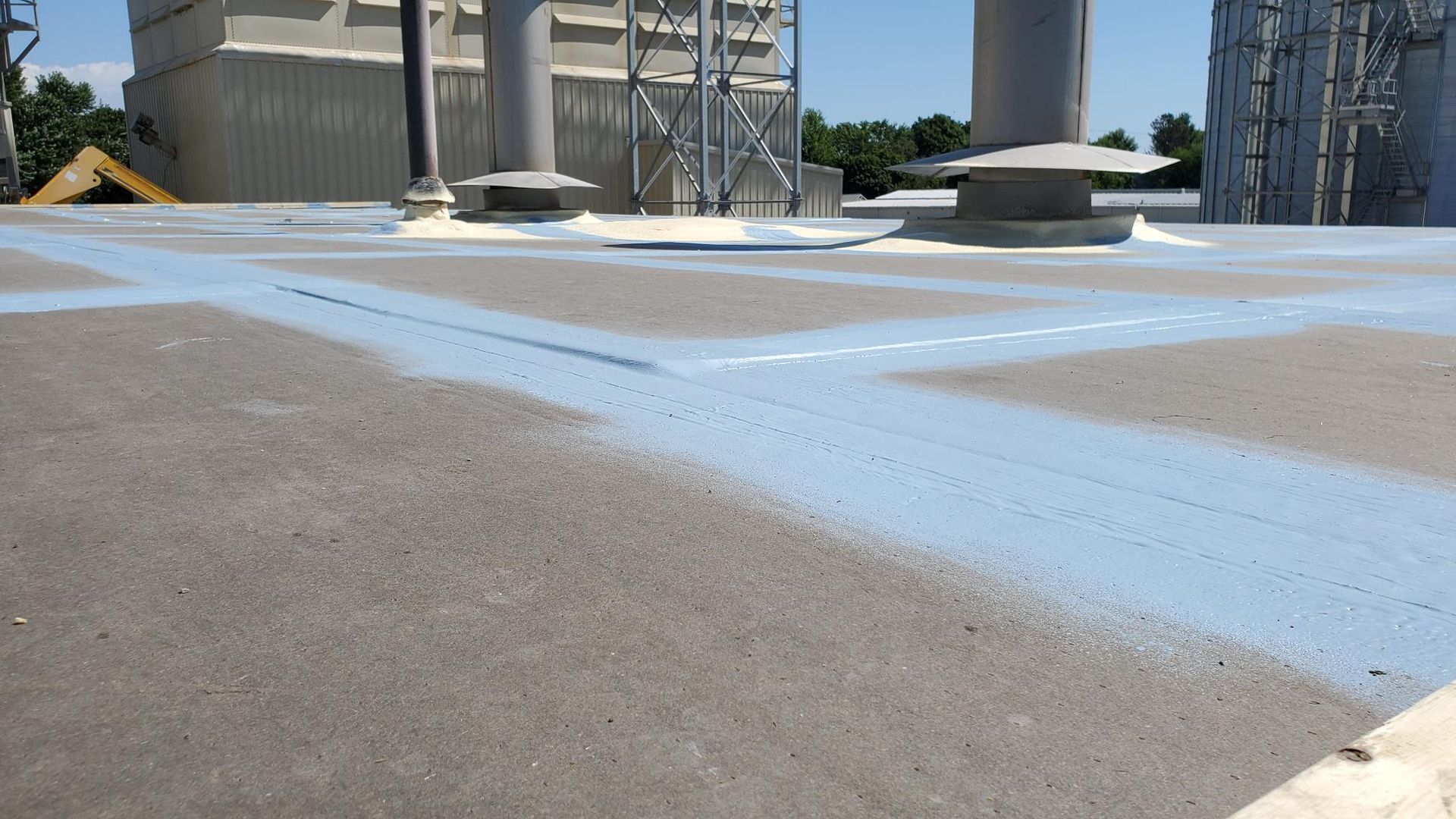 The roof of a building is being painted blue.