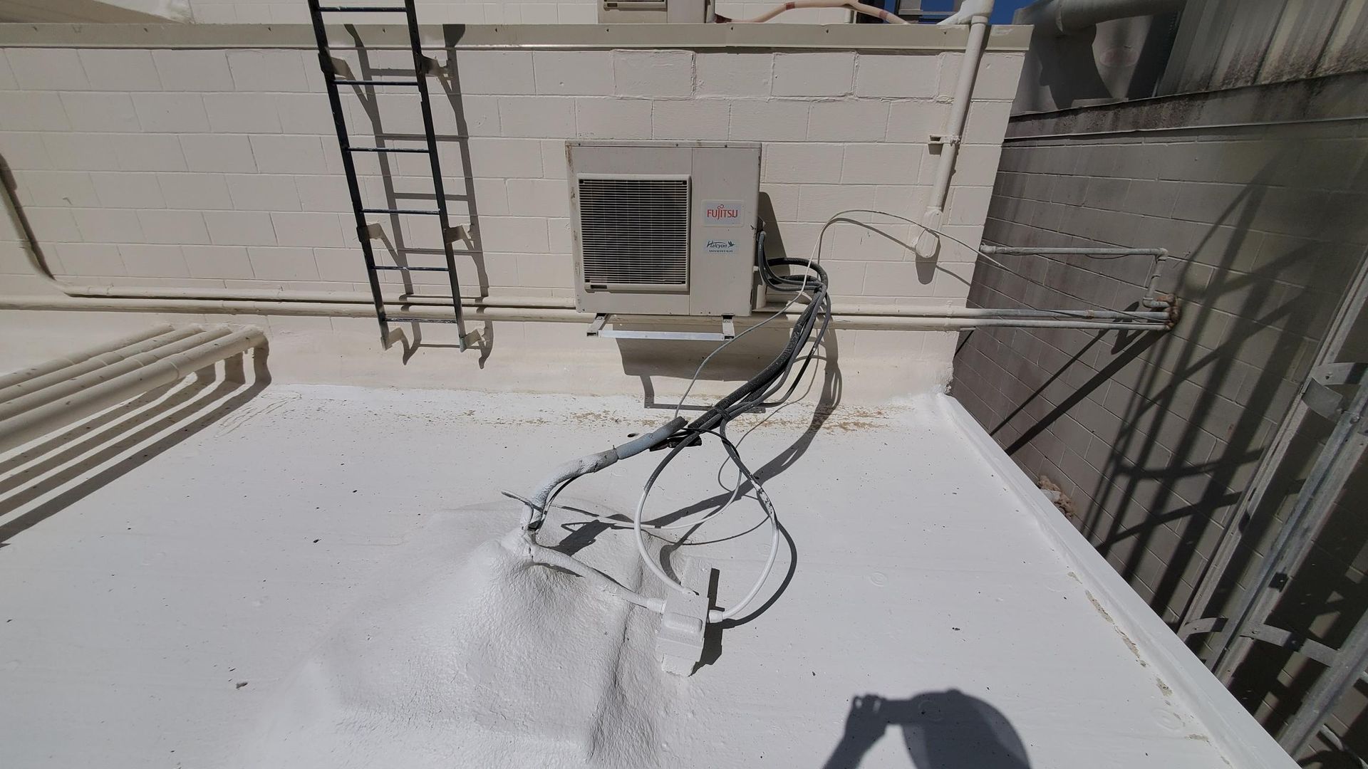 A white roof with a ladder and a fan on it.