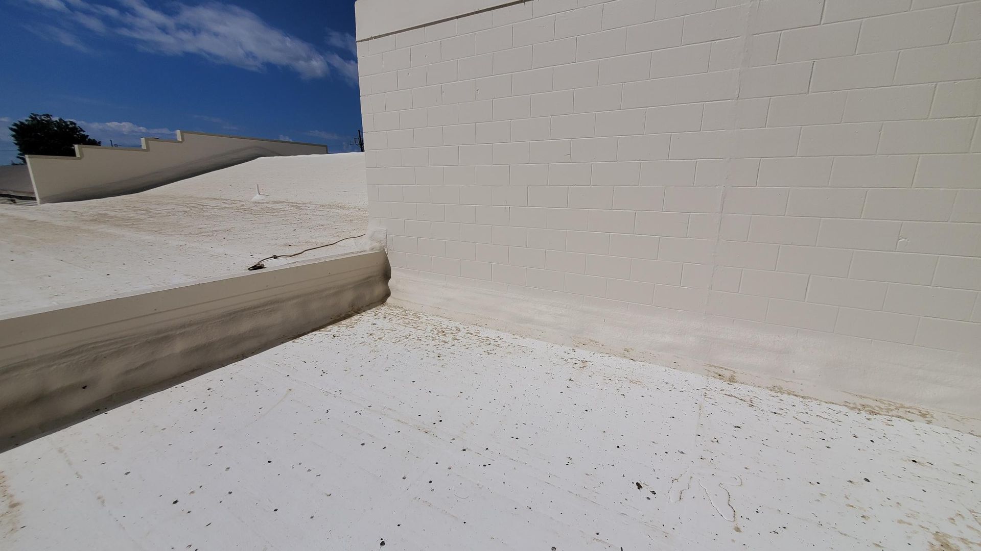 A white wall with a blue sky in the background and a white roof.