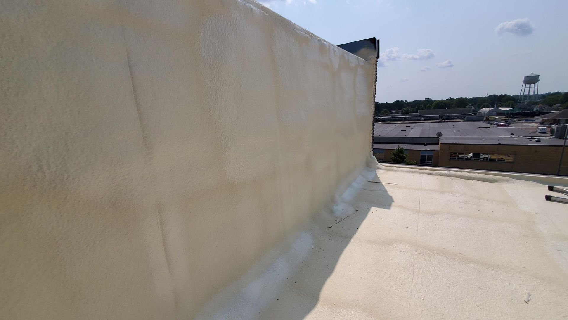 A roof with a wall and a water tower in the background.